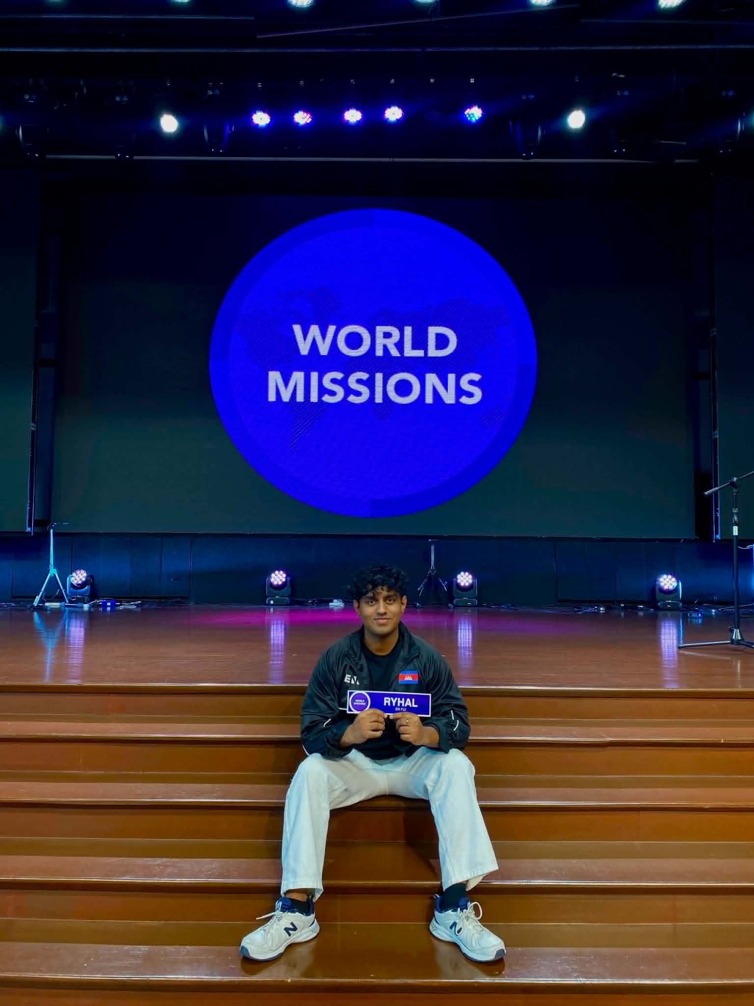 Ryhal Kumar seated beneath the World Missions sign
